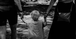 grayscale photo of woman in black dress holding child in black shirt
