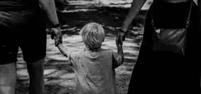 grayscale photo of woman in black dress holding child in black shirt